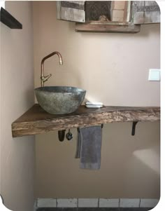 a bathroom sink sitting on top of a wooden shelf next to a mirror and towel rack