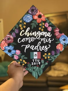 someone is holding up a graduation cap with flowers on it