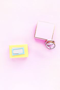 two wedding rings sitting on top of a pink surface next to a box with a ring in it