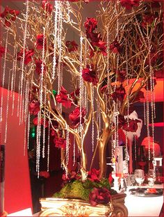 a tree with red flowers and beads hanging from it's branches in front of a mirror