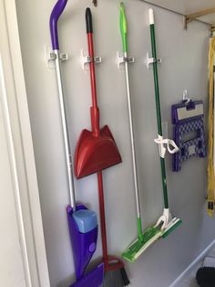 several different types of brooms and mops hanging on the wall next to each other