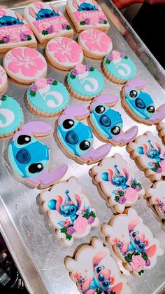 cookies decorated with blue, pink and purple icing are on a cookie sheet in the shape of cartoon characters