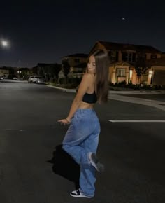 a woman standing in the middle of an empty street at night with her hand on her hip