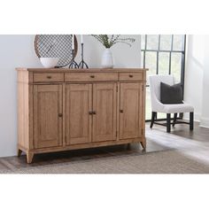 a large wooden cabinet sitting on top of a rug next to a chair and window