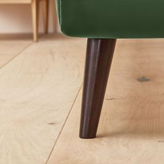 a green chair sitting on top of a hard wood floor next to a wooden table