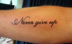 a person with a tattoo on their arm that says never give up and the words are written in cursive font