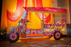 an elaborately decorated horse drawn carriage in front of yellow drapes and red curtains