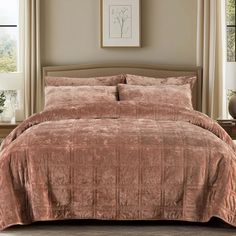 a bed covered in a pink comforter and pillows