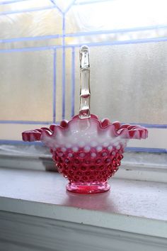 a pink and white bowl sitting on top of a window sill