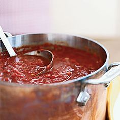 a large pot filled with red sauce on top of a wooden table