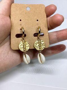 A beautiful handmade pair of gold plated brass disc cowrie shell earrings versatile enough to wear every day, and suit any occasion. Earrings made with cowrie shells and gold plated metal brass disc beads. Lightweight and easy to wear, these dangle earrings are 5 cm long with 24K gold plated hoops. Cowrie Shell Hammered Disc Hoop Earrings made with materials: -24K Gold Plated leverback hoops earring measures 15 mm diameter 1.6cm long -hammered gold spacer disc  beads matte gold plated brass 15 m Bohemian Hoop Earrings For Beach, Gold Drop Earrings For Vacation, White Hoop Earrings For Vacation, Beachy Gold Jewelry For Vacation, Beachy Gold Vacation Jewelry, Beachy Gold Dangle Earrings, Gold Dangle Earrings For Beach Season, Handmade Hoop Earrings For Summer Vacation, Handmade Dangle Hoop Earrings For Vacation