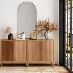 a large mirror sitting on top of a wooden cabinet next to a vase filled with flowers