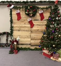 a christmas display with stockings and presents hanging on the wall next to a wooden board