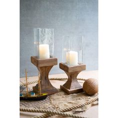 two candles sitting on top of a rope next to a wooden container filled with water