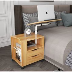 a bed with a laptop on top of it next to a night stand and nightstand