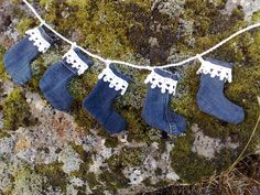 three pairs of blue jeans hanging from a line on moss covered rock with white lace