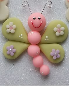 a pink and green butterfly with flowers on it's wings, sitting next to two smaller ones