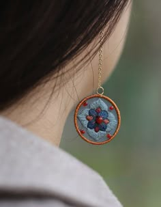 a close up of a woman's ear wearing a necklace with flowers on it