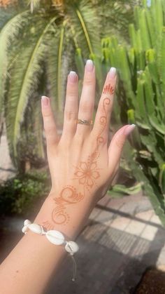 a woman's hand with a tattoo on her left wrist and palm trees in the background