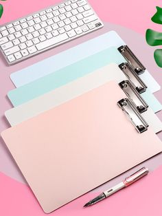 three notebooks and a keyboard on a pink background