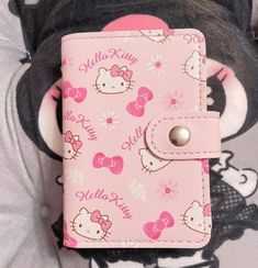 a pink hello kitty wallet is laying on top of a teddy bear's pillow