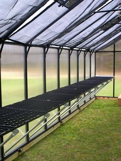 the inside of a greenhouse with several rows of benches in front of it and grass on the ground