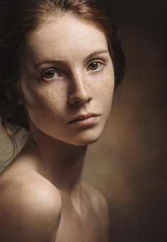 a woman with freckled hair is posing for a photo in front of a dark background