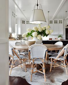 a dining room table and chairs with flowers in the center surrounded by rugs on the floor