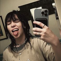 a woman taking a selfie with her cell phone in front of her face and tongue out