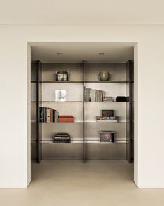 an open bookcase with many books on it's shelves in a white room