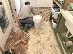 two men working on a brick floor in a bathroom