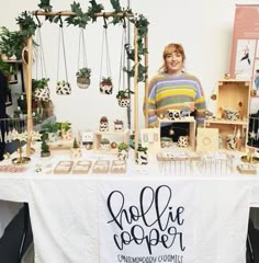 a woman standing in front of a table with plants on it and other items for sale