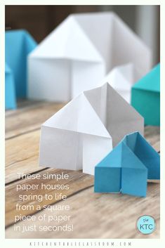 paper houses sitting on top of a wooden table with text overlay that reads, these simple paper houses spring to life from a square piece of paper in just seconds