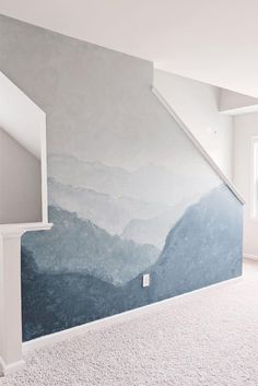 an empty room with mountains painted on the wall and carpeted flooring in front of it