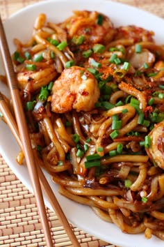 a plate with noodles, shrimp and scallops on it next to chopsticks