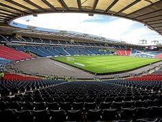 an empty stadium filled with lots of seats and one soccer field in the middle of it