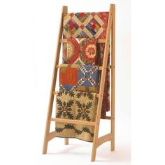 a wooden display rack with quilts and pillows on the top, in front of a white background