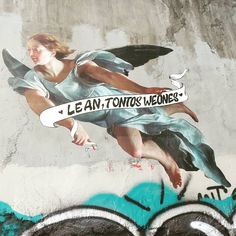 a woman is painted on the side of a wall with words and an angel holding a skateboard