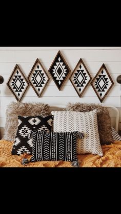 a bed topped with lots of pillows next to a wall mounted art above it's headboard