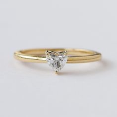 a yellow gold ring with a heart shaped diamond on the top and bottom, set against a plain white background