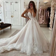 a woman in a wedding dress taking a selfie with her cell phone while looking into the mirror