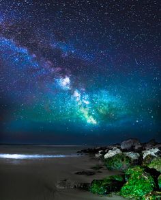 the night sky is filled with stars and bright green lights, as well as some rocks