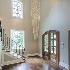 a large foyer with wooden floors and chandelier hanging from the ceiling above it