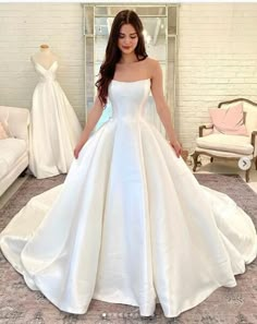 a woman standing in front of a dress on display at a bridal shop wearing a white wedding gown