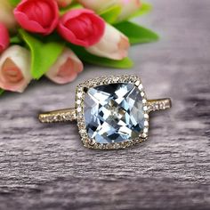 an engagement ring with a cushion cut blue topazte surrounded by white and pink flowers