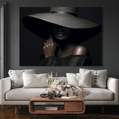 a woman with a large hat on her head is standing in front of a couch