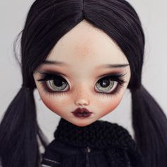 a doll with long black hair and brown eyes is wearing a black sweater, dark lipstick