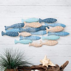 a group of blue and white fish sitting on top of a wooden table next to a potted plant