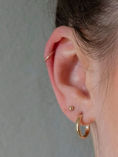 a close up of a person's ear with two small gold hoops on it