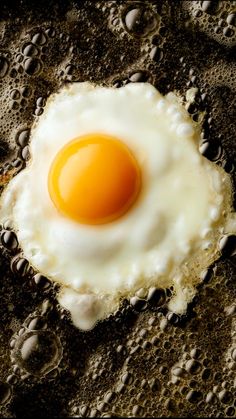 an egg is sitting in the middle of some oil on top of brown and white bubbles